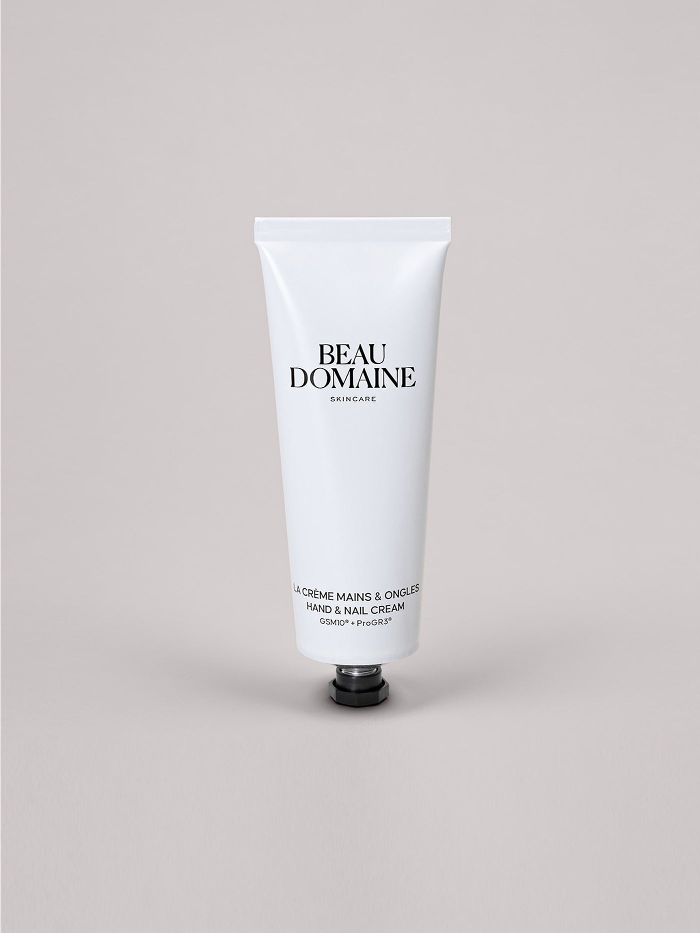 White tube of Beau Domaine hand and nail cream on a light gray background
