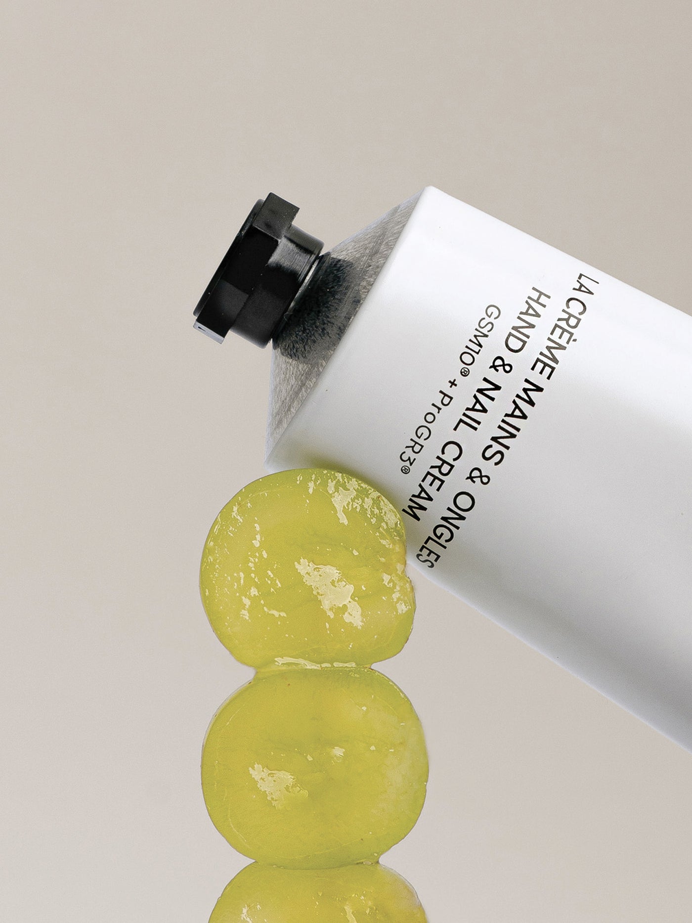 Hand cream tube with grapes on a neutral background