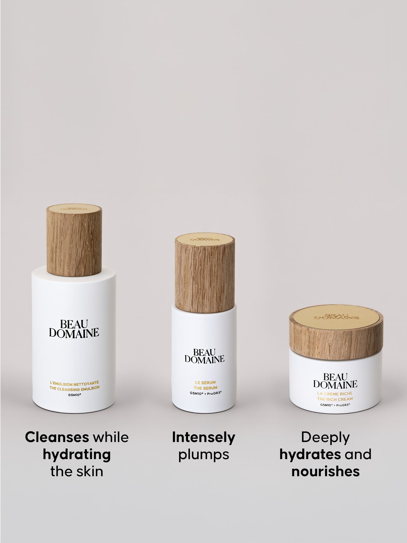 Three Beau Domaine products containing Cleansing Emulsion, Serum, and Rich Cream in its jar, all three arranged in a row, with a plain beige background and a caption presenting the products below each one. 