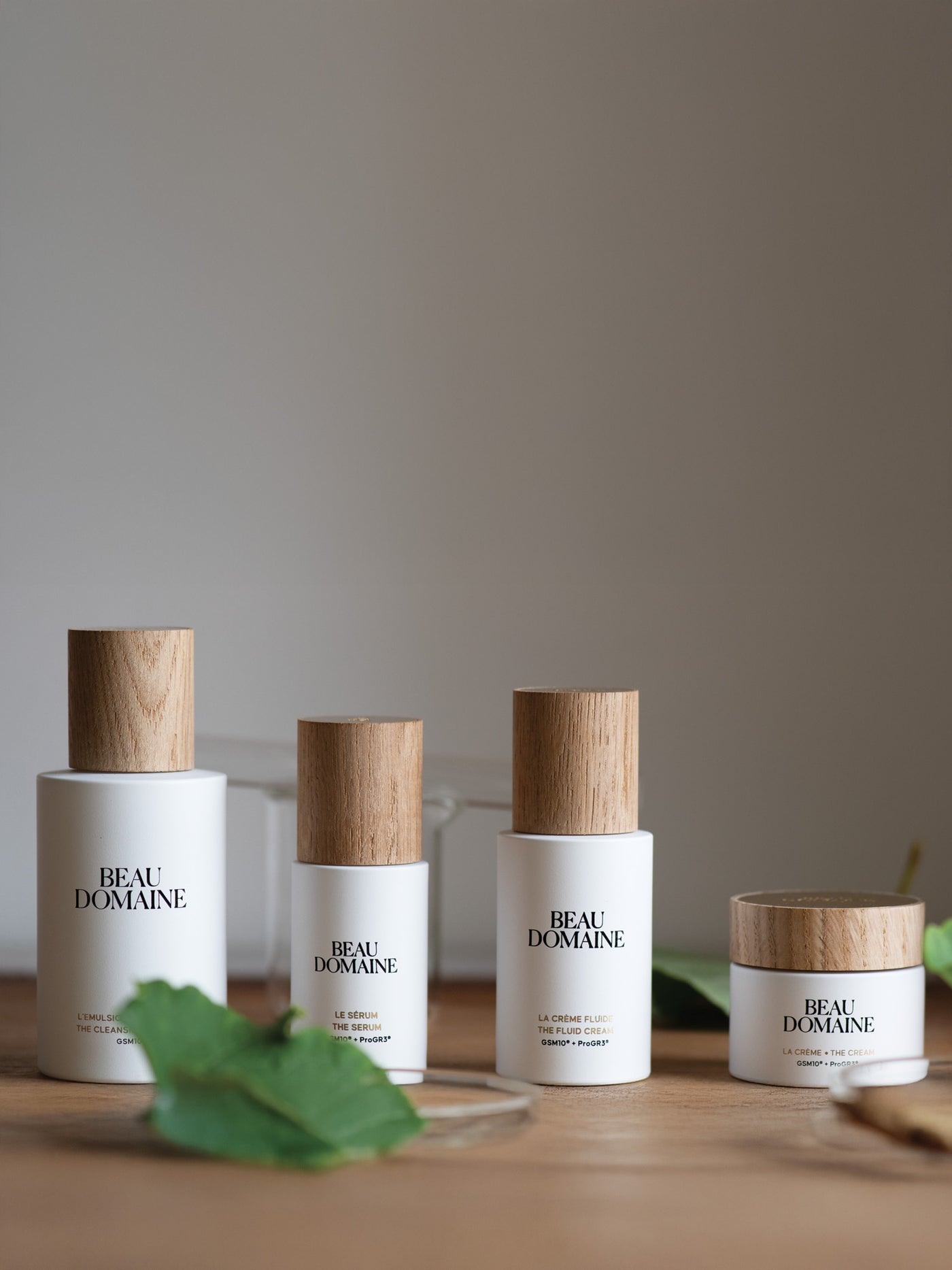 Four 'Beau Domaine' skincare products on a wooden surface with a neutral background