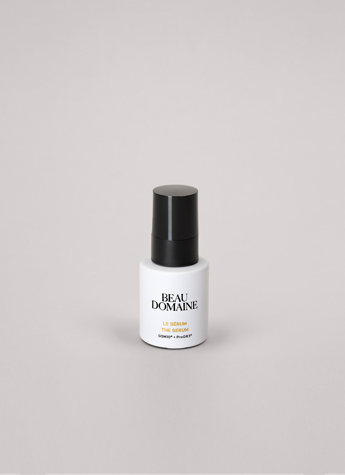 White serum bottle with black cap on a light gray background